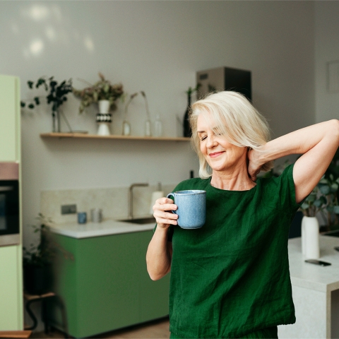 Nainen kahvikupin kanssa keittiössä