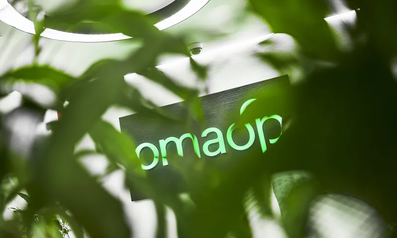 Vihreiden lehtien takaa pilkistää OmaSp:n logo