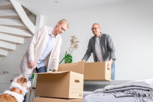 Mies, nainen ja koira muuttolaatikoiden keskellä