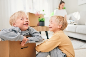 Lapset leikkivät muuttolaatikoilla aikuisen pakatessa.