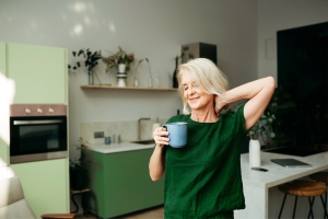Nainen kahvikupin kanssa keittiössä
