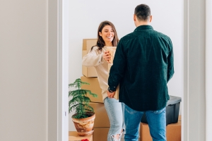 Kaksi henkilöä kokoaa asunnossa muuttolaatikoita.